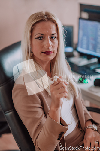 Image of A businesswoman sitting in a programmer's office surrounded by computers, showing her expertise and dedication to technology.