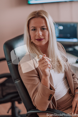 Image of A businesswoman sitting in a programmer's office surrounded by computers, showing her expertise and dedication to technology.