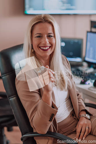 Image of A businesswoman sitting in a programmer's office surrounded by computers, showing her expertise and dedication to technology.