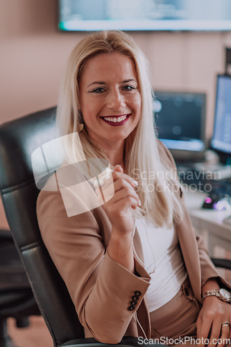 Image of A businesswoman sitting in a programmer's office surrounded by computers, showing her expertise and dedication to technology.