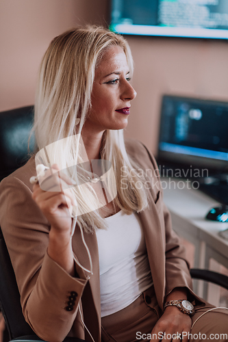 Image of A businesswoman sitting in a programmer's office surrounded by computers, showing her expertise and dedication to technology.