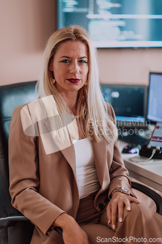 Image of A businesswoman sitting in a programmer's office surrounded by computers, showing her expertise and dedication to technology.