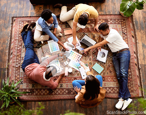 Image of Teamwork, creative and overhead with a designer team lying on the floor while working on a project. Collaboration, startup or ideas with a group of young people working in advertising or marketing