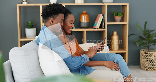 Image of Internet, technology and couple with phone on sofa in living room. Black man teaching young woman how to use banking app, online shopping or fintech on a smartphone, while sitting on a couch at home.