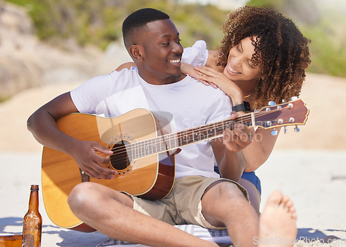 Image of Romance, music and interracial couple with a guitar at the beach, bonding and entertainment. Love, happiness and black man playing a song on an instrument with a woman listening at the ocean