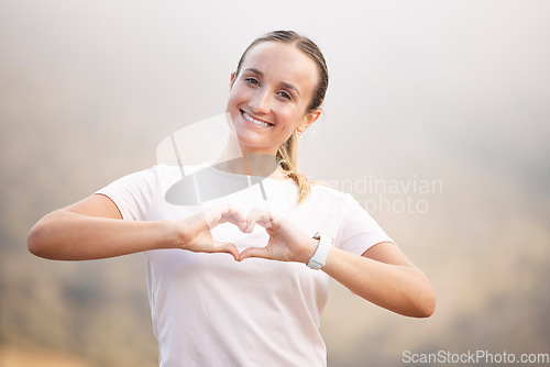 Image of Portrait, runner and hand sign by woman with heart, symbol or gesture for wellness against blurred background. Face, happy and girl with emoji hands, shape and message for self love, peace and care