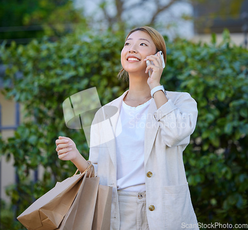 Image of Phone call, Asian woman and retail shopping bag of a gen z person with mobile outdoor. Happy, communication and conversation after shop discount sale and promotion at a mall or luxury boutique