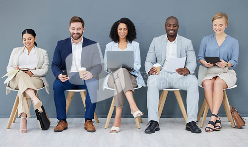 Image of Business people, diversity and networking in row for recruitment, interview or corporate meeting at office. Group of diverse candidates sitting in waiting room working with technology for team hiring