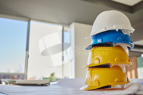 Image of Building, helmets and architect equipment on table for construction safety, security or industrial work gear at office. Stack of hard hats on desk for safe engineering or contracting for architecture