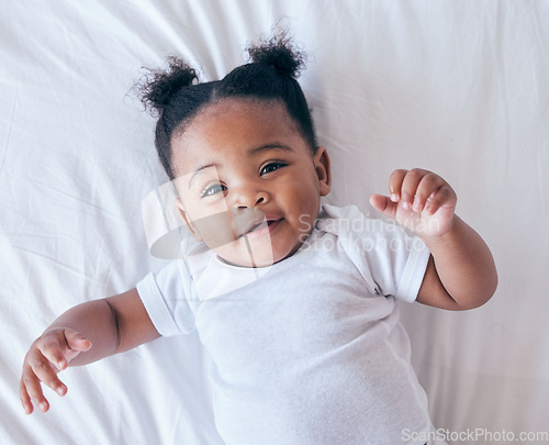 Image of Above, portrait and baby relax in bed, happy and content after waking up in her home. Face, toddler and girl smile in a bedroom, lying and playing, curious and sweet on a peaceful morning in nursery