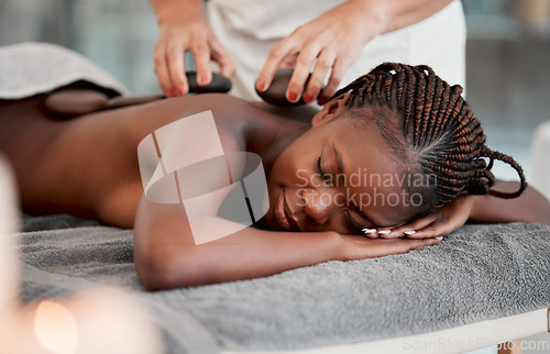 Image of Black woman, hot stone massage and masseuse, hands and zen with holistic therapy and spa treatment. Calm, peace of mind and female, healing and stress relief with self care at wellness resort
