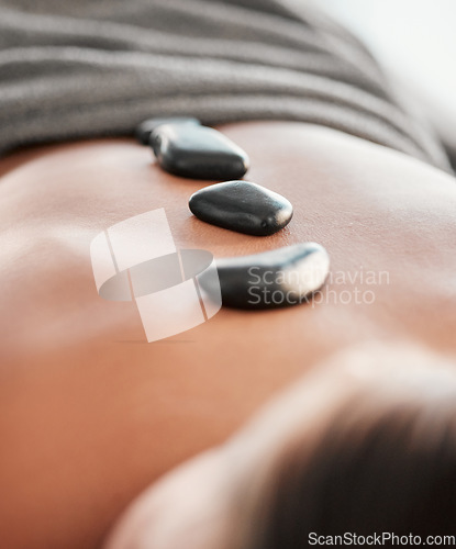 Image of Woman, rocks and back in spa relaxation for treatment, stress relief or massage at resort. Female relaxing with hot stone in physical therapy for skincare, body healing or zen wellness at salon