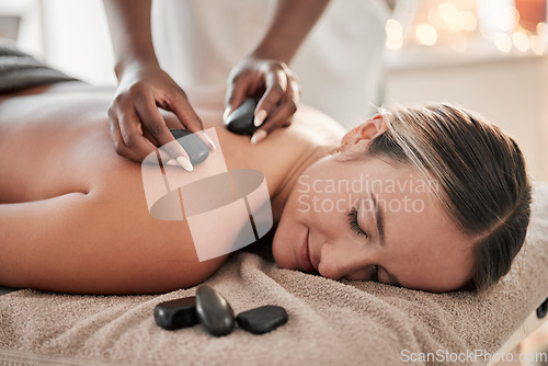 Image of Woman, hot stone massage and therapist, hands and zen with holistic therapy and spa treatment for back. Calm, peace of mind and face, healing and stress relief with self care at wellness resort