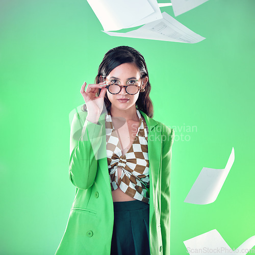 Image of Education, smart and portrait of a woman with glasses isolated on a green background in a studio. Gen z, professor and teacher with paper, school work and tests flying for confidence on a backdrop