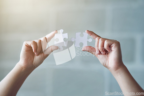 Image of Hands, puzzle and synergy with a business woman in the office against a brick wall for building or connection. Idea, innovation and strategy with a female employee holding jigsaw pieces at work