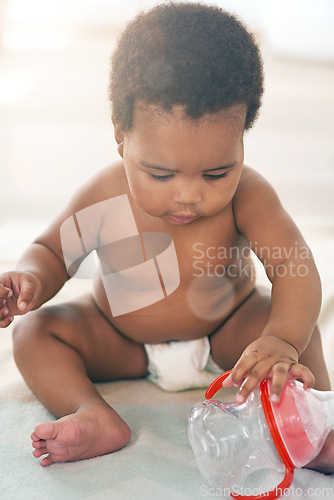 Image of Children, black baby and girl with a bottle sitting on a blanket on the floor of a home for child development. Kids, cute and curious with a newborn infant learning or growing alone in a house