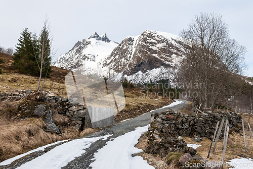 Image of Stone yard with fence over halfway snow-covered mountain road