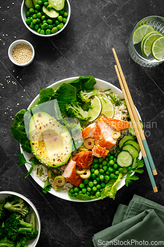 Image of Salmon avocado bowl with broccoli, green peas, rice and fresh salad. Healthy food, top view