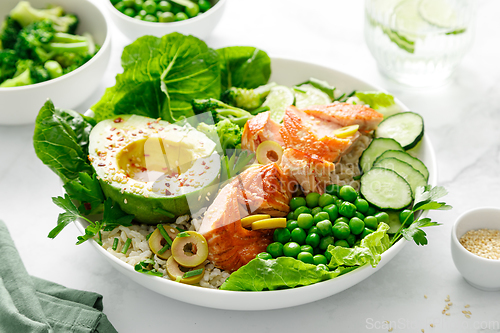 Image of Salmon avocado bowl with broccoli, green peas, rice and fresh salad. Healthy food, top view