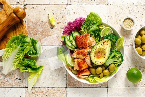 Image of Salmon avocado bowl with broccoli, olives and fresh salad. Healthy food, keto diet, top view