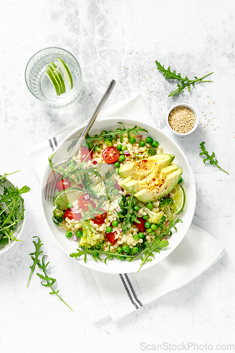 Image of Couscous salad with broccoli, green peas, tomatoes, avocado and fresh arugula. Healthy natural plant based vegetarian food for lunch, israeli cuisine, top view