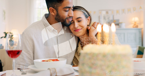 Image of Interracial couple, gift and celebrate birthday being happy, kiss and smile in home at table with cake. Love, man and woman being content, romantic and present being cheerful celebration together.