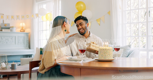 Image of Gift, dinner and couple talking about birthday, anniversary or celebration at a dining room table in house. Happy, smile and young man and woman speaking about present, gratitude and love with food