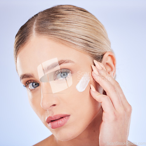 Image of Skincare, face portrait and woman with cream in studio isolated on a blue background. Dermatology closeup, beauty cosmetics and young female model apply hydration lotion, creme or moisturizer product