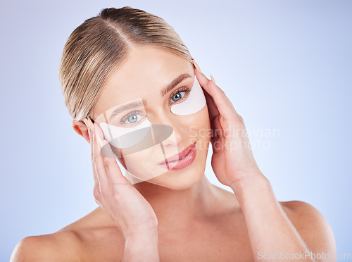 Image of Face portrait, skincare and woman with eye mask in studio isolated on a blue background. Dermatology, makeup cosmetics and beauty of female model with facial patches for healthy skin or collagen.