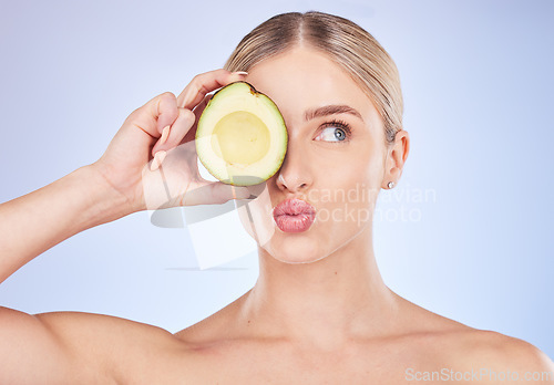 Image of Face, skincare and woman with avocado in studio isolated on a blue background. Cosmetics kiss, fruit and thinking female model with food for omega 3, nutrition or diet, healthy skin or beauty pout.