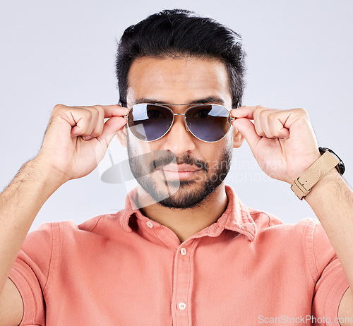 Image of Portrait, sunglasses and man with fashion, trendy and casual clothes against grey studio background. Face, male or gentleman with eyewear, cool or edgy with style, confidence or carefree with success