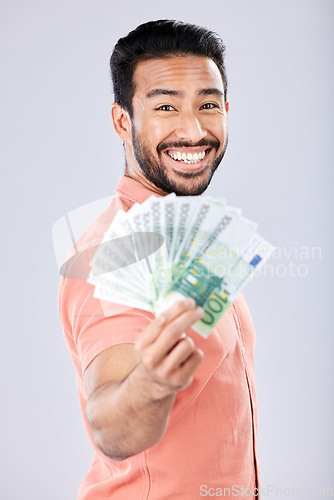 Image of Showing, rich and portrait of Asian man with money isolated on a grey studio background. Finance, wealth and excited person holding cash from investment, lottery and winning the jackpot on a backdrop