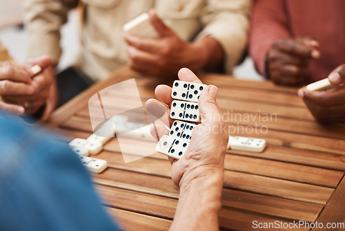 Image of Hands, dominoes and friends in board games on wooden table for fun activity, social bonding or gathering. Hand of domino player holding rectangle number blocks playing with group for entertainment