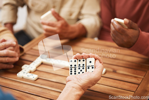 Image of Hands, dominoes and friends in board games on wooden table for fun activity, social bonding or gathering. Hand of domino player holding rectangle number blocks playing with group for entertainment