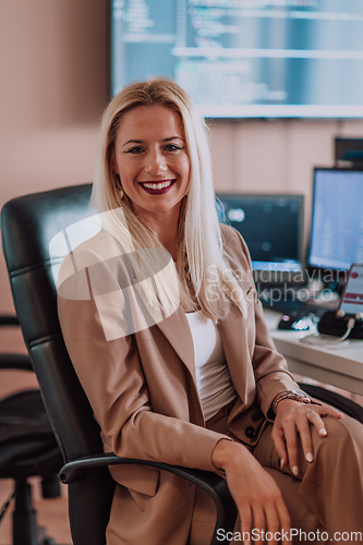 Image of A businesswoman sitting in a programmer's office surrounded by computers, showing her expertise and dedication to technology.