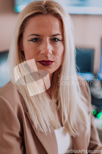 Image of A businesswoman sitting in a programmer's office surrounded by computers, showing her expertise and dedication to technology.