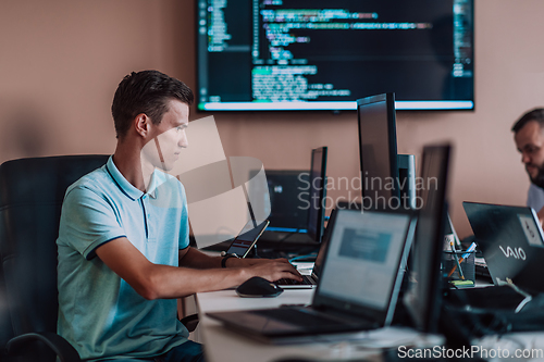 Image of A programmer diligently testing smartphone applications while sitting in their office.