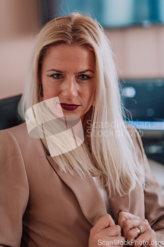 Image of A businesswoman sitting in a programmer's office surrounded by computers, showing her expertise and dedication to technology.