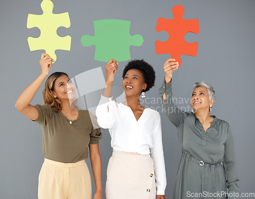 Image of Business people, puzzle pieces and synergy, connection and smile with diversity on studio background. Problem solving, link and working together with teamwork and cooperation with women in corporate