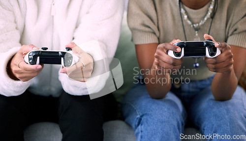 Image of Woman, hands and friends gaming with controller on living room sofa in competitive match or game at home. Women playing video games in competition or esports sitting on lounge couch for entertainment