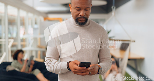 Image of Businessman in office walking, typing on smartphone and greeting people at creative startup. Communication, technology and black man on walk at business checking phone for social media, email or text