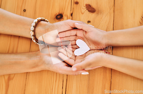 Image of Hands holding, heart and shape of love by parent and child in support, care and unity together on a table in a home. Top view, family and people in adoption with hope symbol and bonding