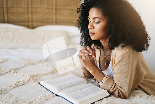 Image of Bible, prayer and black woman praying on bed in bedroom home for hope, help or spiritual faith. God, christian and female worship Jesus or Holy Spirit for forgiveness, compassion or grace in house.