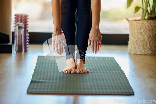 Image of Hands, feet and yoga with a woman in her home for a mental health, fitness or wellness workout. Exercise, pilates or stretching and a female yogi training with a forward bend alone for zen