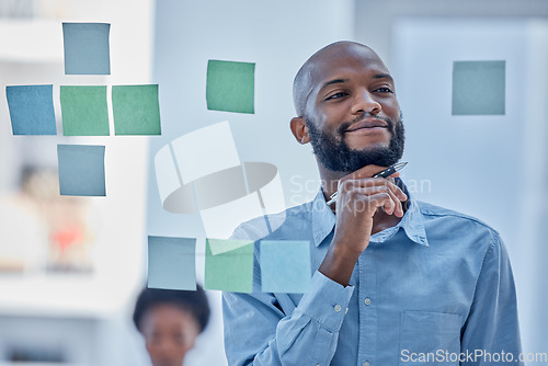 Image of Black man, writing and thinking in planning schedule on glass board for brainstorming tasks at office. African male wondering in thought for project plan, idea or sticky note for company strategy