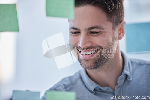 Image of Creative man, writing and smile for schedule planning on glass board for brainstorming tasks at office. Happy male face smiling in project plan, write or sticky note for company strategy or startup