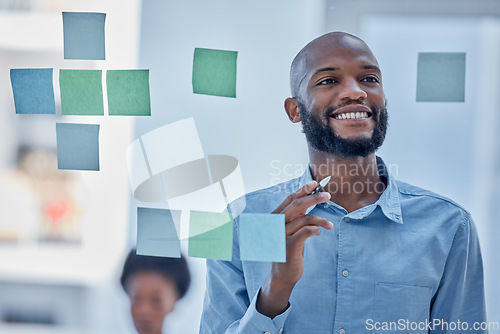 Image of Black man, writing and planning schedule with smile on glass board for brainstorming tasks at office. Happy African American male smiling in project plan, idea or sticky note for company strategy