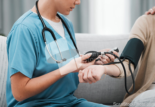 Image of Blood pressure, caregiver nurse and woman patient on a nursing home for health and wellness check. Healthcare, doctor and living room consultation for medical test in retirement on a lounge couch