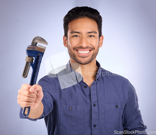Image of Man, smile and portrait with tools or wrench for handyman, maintenance or repair work in studio. Happy asian model person on purple background show spanner for engineer, mechanic or technician job