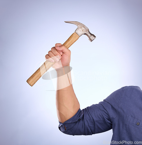 Image of Hammer, construction worker tool and hand in a isolated, blue background and studio. Handyman, house building and maintenance contractor career with man hands holding a builder and repair tools